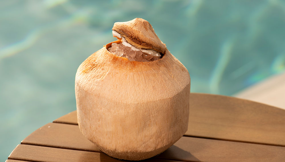 Open coconut sitting in front of pool