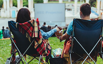 Couple sitting in lawn chairs and sharing a snack at an outdoor